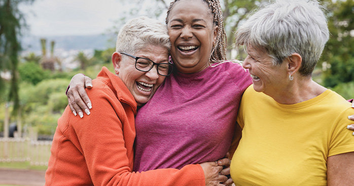 3 elderly women laughing and hugging